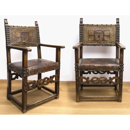 Zwei Stühle. Nussbaum, Lederbespannung. Pfostenfüße, tw. geschnitzt. Oberitalien. Besch., rest., erg.  H. 122 cm.
