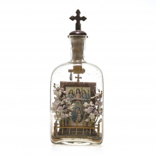 Flascheneingericht. Süddeutsch, Ende 19. Jh. Farbloses Glas, darin Rahmen mit Druckbildern und Stoffblüten. H. 31 cm.