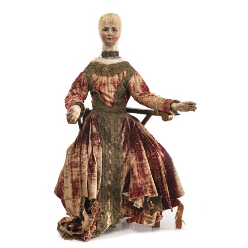 Gliederpuppe/Kostümfigur. Süddeutsch, 18. Jh. Arme beweglich, Körper aus Holz, übergangene Farbfassung. H. (mit Stuhl) 87 cm.