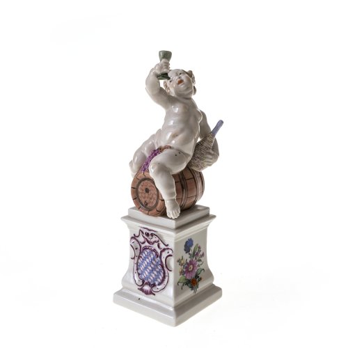 Putti auf einem Weinfass mit Traube. Porzellan, farbig staffiert. Gemarkt. Nymphenburg. H. 17,3 cm.