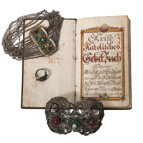 19. Jh. Zwei Florschnallen, eine Kropfkette mit Farbsteinbesatz, ein Trachtenring und ein katholisches Gebetsbuch von 1809. Gebrauchsspuren.