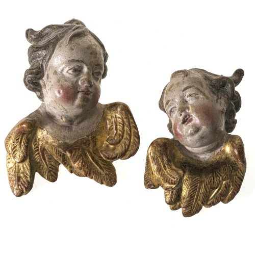 Zwei Puttenköpfe. Bayern, 18. Jh. Holz, übergangene Farb- und Goldfassung.  H. ca. 24 und 19 cm. Minimal besch.