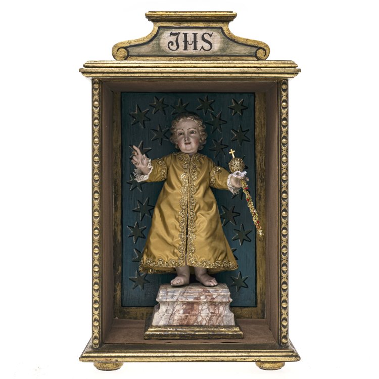 Italien, 18. Jh. Jesusknabe als Salvator mundi. Holz, geschnitzt, vollplastisch gearbeitet. Übergangene Inkarnatfassung, mit Glasaugen. Rep., besch., zwei Finger fehlend. Auf Podest montiert, H. ca. 7 cm. Jesusknabe H. ca. 26,5 cm. Neuzeitlicher Schrein. 50 x 30 x 21,5 cm. Hauptbild zu Objekt, Italien, 18. Jh. Jesusknabe als Salvator mundi. Holz, geschnitzt, vollplastisch gearbeitet. Übergangene Inkarnatfassung, mit Glasaugen. Rep., besch., zwei Finger fehlend. Auf Podest montiert, H. ca. 7 cm. Jesusknabe H. ca. 26,5 cm. Neuzeitlicher Schrein. 50 x 30 x 21,5 cm.,