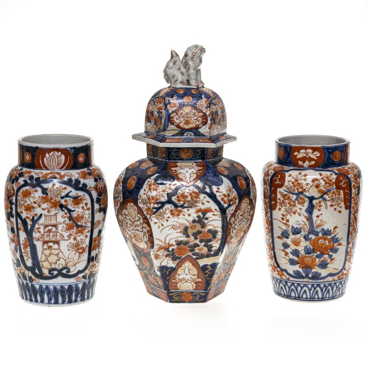 Deckelvase und Vasenpaar. Südostasien. Porzellan, Emailmalerei in Rot und Blau, Fohundbekrönung. H. 24-40 cm. Hauptbild zu Objekt, Deckelvase und Vasenpaar. Südostasien. Porzellan, Emailmalerei in Rot und Blau, Fohundbekrönung. H. 24-40 cm.,