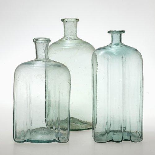 Drei Vierkantflaschen. Deutsch. Hellgrünes Glas. Eine mit leichter Kratzspur. H. 30-35 cm.