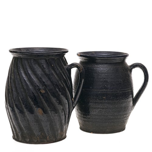 Zwei Krüge. Irdenware, dunkelblau glasiert, einer schräg gerippt. Best. H. 21-22 cm.