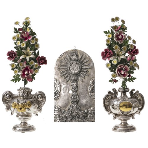 Süddeutsch, 19. Jh. Zwei Altarvasen, Holz  geschnitzt. Übergangene Silber- und Goldfarbe. Blüten aus Metall. Tw. leicht besch. H. 62-63 cm.Beschlag einer Tabernakeltür. Silberblech, getrieben.  28 x 15,5 cm. Besch., rep.