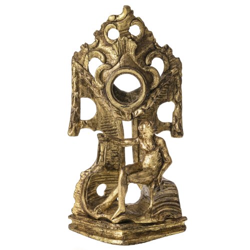 Taschenuhrenständer. Um 1800. Holz, geschnitzt, Goldfassung. Empirefestons, im Vordergrund stilisierter Chronos mit Stundenglas. Besch., rep. H. 29 cm.