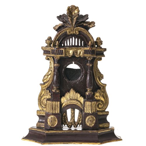Taschenuhrenständer. Süddt., 18./19. Jh. Holz, geschnitzt, Farb- und Goldfassung. Klassizistische und barocke Stilelemente. Minim. besch. H. ca. 33,5 cm.