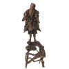 China. Figur des Gottes Shoulao, Wurzelholz. Schnitzerei aus mehreren Segmenten zusammengesetzt. Zwei Teile, Figur auf Holzgestell. Eingesetzte Glasaugen, eines fehlt. Teilw. besch., Daumen fehlt. H. ca. 60,5 cm.