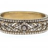 Armreif. 14 K GG. Obere Hälfte mit floralem Band, mit Saatperlen und Brillanten dekoriert, zentrale Blüte mit weiteren Brillanten belegt.