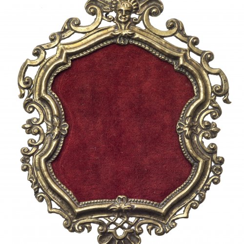 Rähmchen. Österreich, um 1720. Messingblech, getrieben, mit Rückwand. Passig geschweift mit getriebenem Engelskopf vor Muschel. Außenmaß 14,5 x 11 cm.