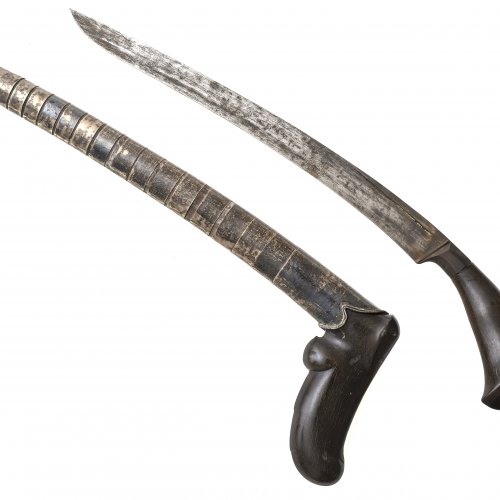 Messer (Bade-Bade). Griff aus Horn. Gekrümmte Klinge, innen geschärft. Scheide mit Silbermanschetten. Malaysia. Leicht besch. L. 35 cm.