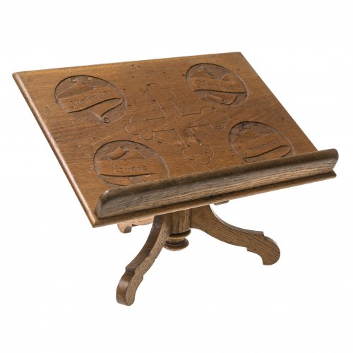 Messbuchständer. Eiche. Auf Dreibeinfuß, Buchablage mit flach geschnitzten  Evagelistennamen, im Zentrum Kreuz. Fleckig. H. 30,5 cm.