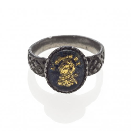 Ring. Weißmetall. Ringkopf blau emailliert mit vergoldetem Herrenporträt unter Glas, Schiene mit graviertem Rautendekor. Alterungsspuren. Ringweite 64.